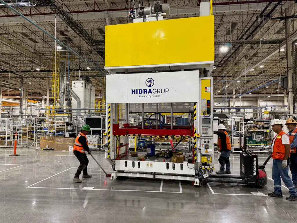 Cuadrilla moviendo una prensa con patines dentro de la nave